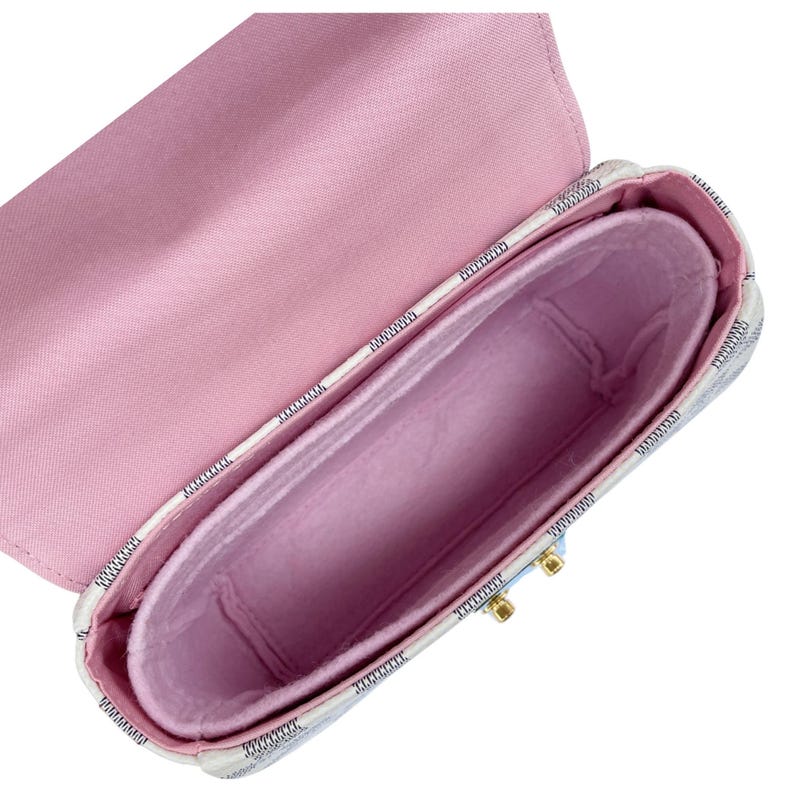 Op de afbeelding: Witte en lichtblauwe handtas met roze binnenkant, open om een roze vilten organizer te onthullen. De tas heeft een rechthoekige vorm en een klepsluiting. Afmetingen in centimeters.