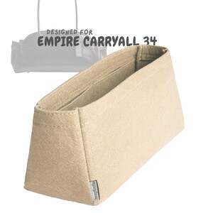 May include: Beige felt bag organizer with the text "DESIGNED FOR EMPIRE CARRYALL 34". The organizer has a rectangular shape with a structured design, featuring interior pockets and a small label on the side.