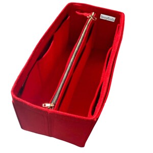 May include: A vibrant red felt handbag organiser with several compartments and a central zipped section. The organiser features a gold-coloured zip and the text "funnykrafts". This accessory is designed to keep handbags tidy.