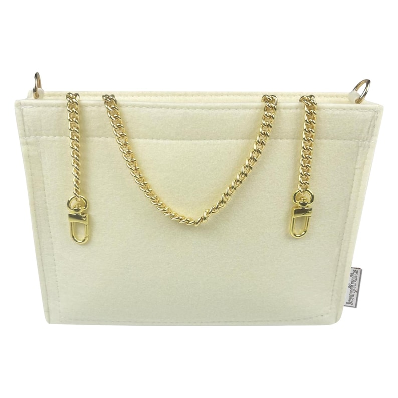 May include: Cream-coloured felt handbag organiser with gold-tone chain straps and hardware. The organiser has a rectangular shape with a pocket on the front and a small tag on the side.