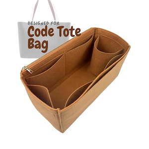 May include: A tan felt tote bag organizer with multiple compartments and a gold zipper. The organizer is designed to fit inside a tote bag, with the words "DESIGNED FOR Code Tote Bag" printed on a white tote bag in the background.