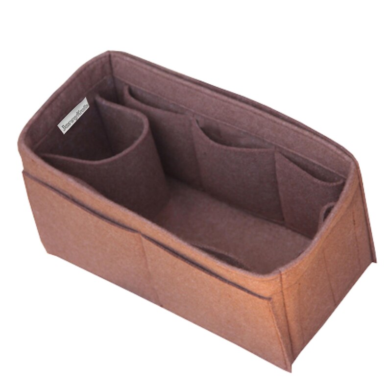 May include: A brown felt handbag organizer insert with a rectangular shape, featuring multiple interior compartments and pockets of varying sizes for storage. A small white fabric tag with the text "JennyKraft" is attached to the inner side.