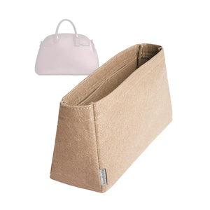 Peut inclure: Un organisateur de sac à main en feutre beige avec plusieurs compartiments. L'organisateur est rectangulaire avec un design structuré et une petite étiquette sur le côté. Un sac à main rose clair est visible en arrière-plan.