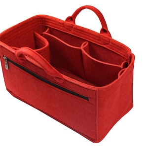 May include: Red felt organizer with multiple compartments and a zippered pocket. The organizer has two handles and is designed to fit inside a larger bag.