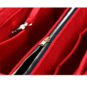 Pode incluir: Organizador de bolsa de feltro vermelho com um z&iacute;per preto e um puxador de z&iacute;per dourado. O organizador tem v&aacute;rios compartimentos para organizar uma bolsa.