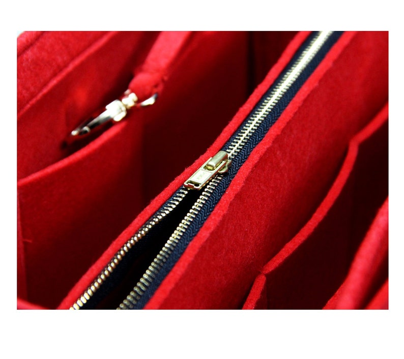 Pode incluir: Organizador de bolsa de feltro vermelho com um z&iacute;per preto e um puxador de z&iacute;per dourado. O organizador tem v&aacute;rios compartimentos para organizar uma bolsa.