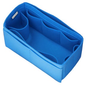 May include: A bright blue felt handbag organizer insert with a rectangular shape, featuring multiple interior compartments and pockets of varying sizes for storage. A small white fabric tag with black text is attached to the inner top edge.