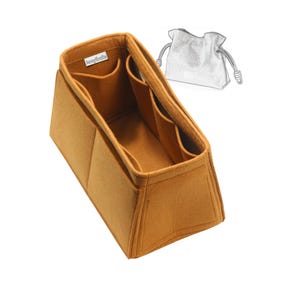 May include: A mustard-colored felt bag organizer with multiple pockets. The organizer has a rectangular shape with a trapezoidal design. A small, white tag is visible on the inside. A sketch of a drawstring bag is in the background.