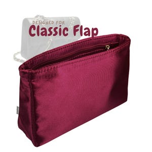 May include: A burgundy-colored Classic Flap handbag organizer with a zippered top. The organizer is made of a smooth, satin-like material. The text "DESIGNED FOR Classic Flap" is displayed in the upper left corner.