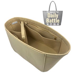 May include: Beige felt bag organizer with multiple compartments and a zippered pocket. Features a detachable strap and gold-tone hardware. The text "Designed For Daily Battle" is visible in the upper right corner, along with the numbers 19-27-35-41.