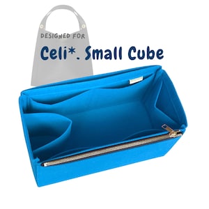 Puede incluir: Organizador de bolso de fieltro azul brillante con múltiples compartimentos y cierre de cremallera. El texto "Designed for Celi*. Small Cube" es visible. El organizador está diseñado para encajar dentro de un bolso.