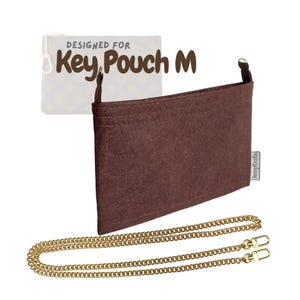 May include: A brown felt organizer designed for a Key Pouch M, with a gold-colored chain strap. The text "DESIGNED FOR Key Pouch M" is visible in the background. The organizer has a rectangular shape.