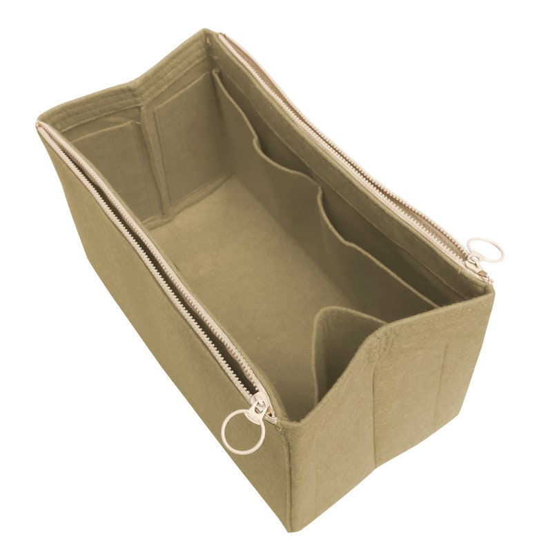 Puede incluir: Organizador de bolso de fieltro beige con m&uacute;ltiples compartimentos y cierre de cremallera. El organizador tiene dos tiradores de cremallera con anillos met&aacute;licos.