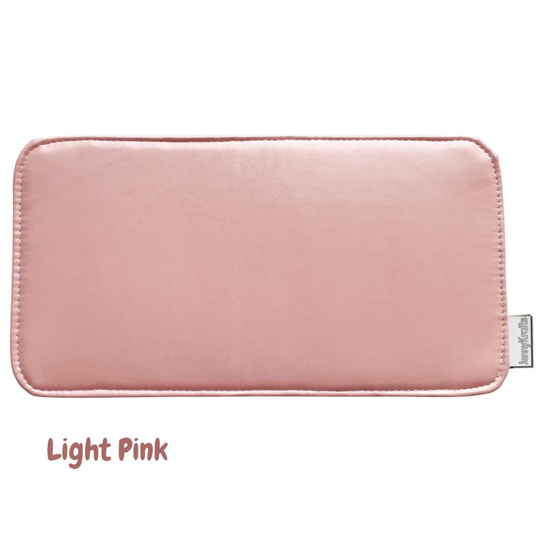 May include: A light pink rectangular item with rounded corners. The item has a stitched border and a small tag on the right side. The text "Light Pink" is displayed at the bottom of the image.