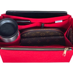 May include: Red felt bag organiser with multiple compartments, including a zipped pocket, a slot for a tablet, and a pocket for a water bottle. The organiser is lined with a brown and beige patterned fabric.
