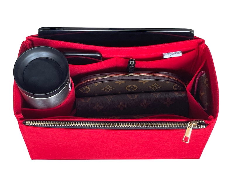 May include: Red felt bag organiser with multiple compartments, including a zipped pocket, a slot for a tablet, and a pocket for a water bottle. The organiser is lined with a brown and beige patterned fabric.