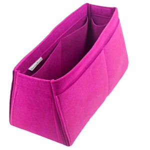 May include: A magenta felt handbag organiser with multiple compartments. The organiser has a rectangular shape with a structured design, featuring several pockets for storage. The brand name is visible on a small label inside the organiser.