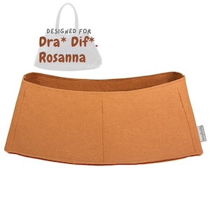 Peut inclure: Organisateur de sac en feutre beige avec un dessus incurvé et une forme rectangulaire. L'organisateur a deux coutures verticales et est conçu pour être placé à l'intérieur d'un sac à main. Le texte "DESIGNED FOR Dra* Dif*. Rosanna" est au-dessus.