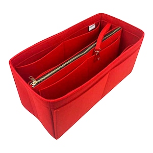 May include: A bright red felt handbag organizer with multiple compartments and a zippered section. The organizer has a gold-colored zipper and a small handle. The interior is divided into several pockets for storage.