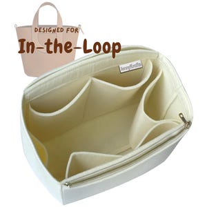 May include: A cream-colored felt handbag organizer insert with multiple interior compartments and a side zipper pocket. A small tag reads JennyKraft. In the background, a light pink tote bag is shown with the text DESIGNED FOR In-the-Loop.