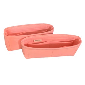 Op de afbeelding: Twee koraalkleurige handtassenorganizers. Elke organizer heeft meerdere compartimenten en een rechthoekige vorm. De merknaam "JennyKrafts" is zichtbaar op een klein label op een van de organizers. De organizers zijn gemaakt van zacht materiaal.