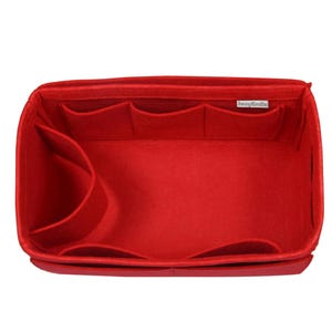 Pode incluir: Organizador de bolsa de feltro vermelho brilhante com vários compartimentos e bolsos. O organizador tem formato retangular com bordas curvas e foi projetado para caber dentro de uma bolsa maior. O interior apresenta bolsos de vários tamanhos.