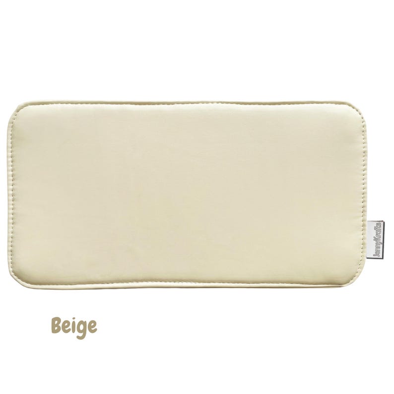 May include: A rectangular beige cushion with rounded corners. The cushion has a stitched border and a smooth surface. The word "Beige" is written in a brown, handwritten font at the bottom of the image.