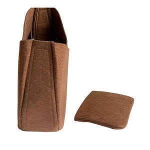 May include: A brown felt bag insert with a separate brown felt base. The insert has a rectangular shape with a slightly curved top and a flat bottom. The base is a flat, rectangular piece of felt.