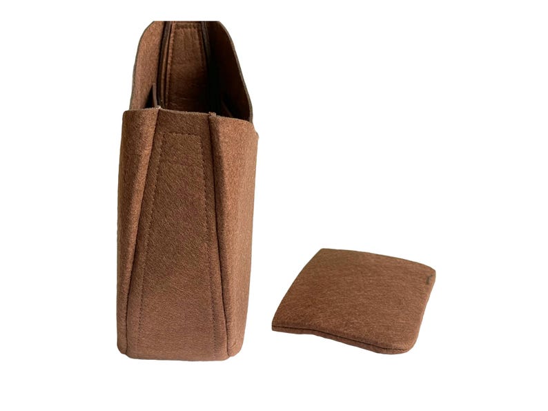 May include: A brown felt bag insert with a separate brown felt base. The insert has a rectangular shape with a slightly curved top and a flat bottom. The base is a flat, rectangular piece of felt.