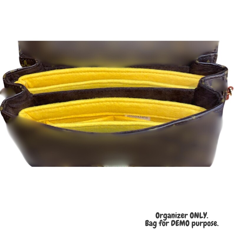 Puede incluir: Organizador de bolso de fieltro amarillo con m&uacute;ltiples compartimentos. El organizador est&aacute; dentro de un bolso de cuero marr&oacute;n. "Jenny's Crafts" est&aacute; impreso en el fieltro.