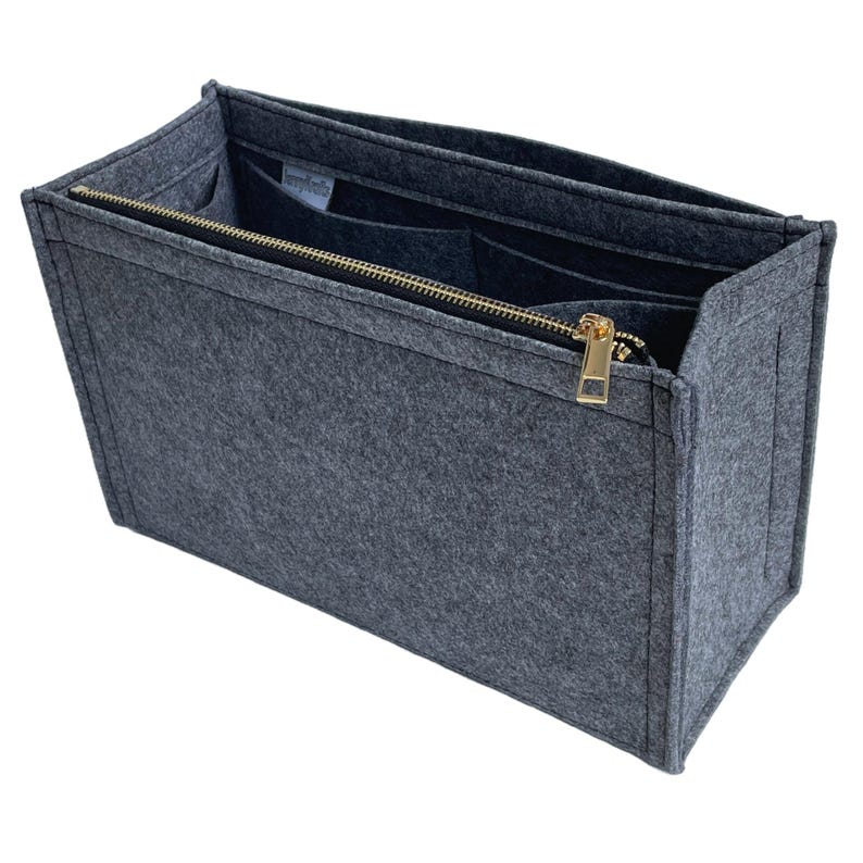 Op de afbeelding: Een grijze vilten handtassenorganizer met meerdere compartimenten en een goudkleurige ritssluiting. De organizer is rechthoekig en ontworpen om in een grotere tas te passen, voor structuur en organisatie.