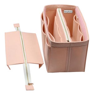 May include: A light peach-colored felt handbag organizer with multiple interior compartments and a removable center section featuring a white zipper. A small white label with the text JennyKraft is attached to the inner wall of the organizer.