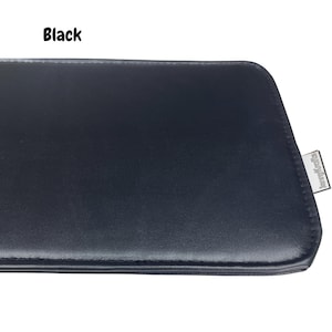 May include: Black rectangular leather case with a stitched edge. The case has a smooth surface and a small silver tag on the corner with the text "JennyKrafts". The word "Black" is printed in white in the upper left corner.