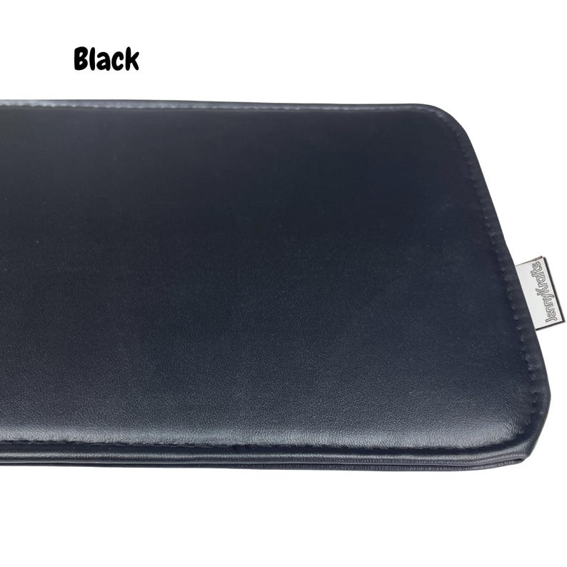 May include: Black rectangular leather case with a stitched edge. The case has a smooth surface and a small silver tag on the corner with the text "JennyKrafts". The word "Black" is printed in white in the upper left corner.