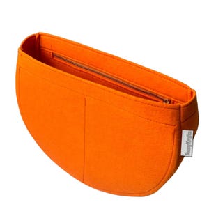 May include: Bright orange felt handbag organizer with a zippered main compartment and two smaller pockets. The organizer has a curved shape and a small tag that reads "JennyKrafts".