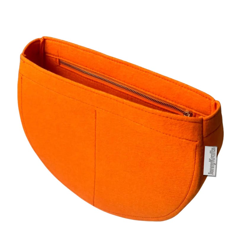 May include: Bright orange felt handbag organizer with a zippered main compartment and two smaller pockets. The organizer has a curved shape and a small tag that reads "JennyKrafts".