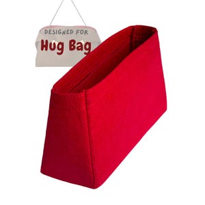May include: A bright red bag organizer with a rectangular shape. The organizer is made of a felt-like material and features the text "DESIGNED FOR Hug Bag" on a sign hanging above it.