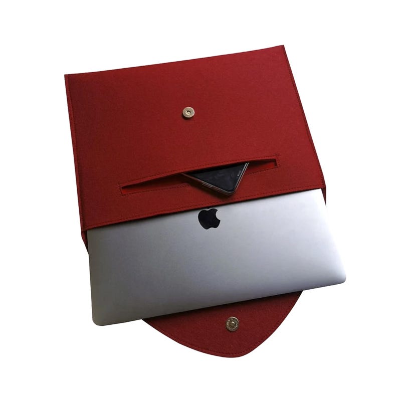 Pu&ograve; includere: Custodia per laptop in feltro rosso con una piccola tasca sul davanti. Un laptop &egrave; all'interno della custodia.