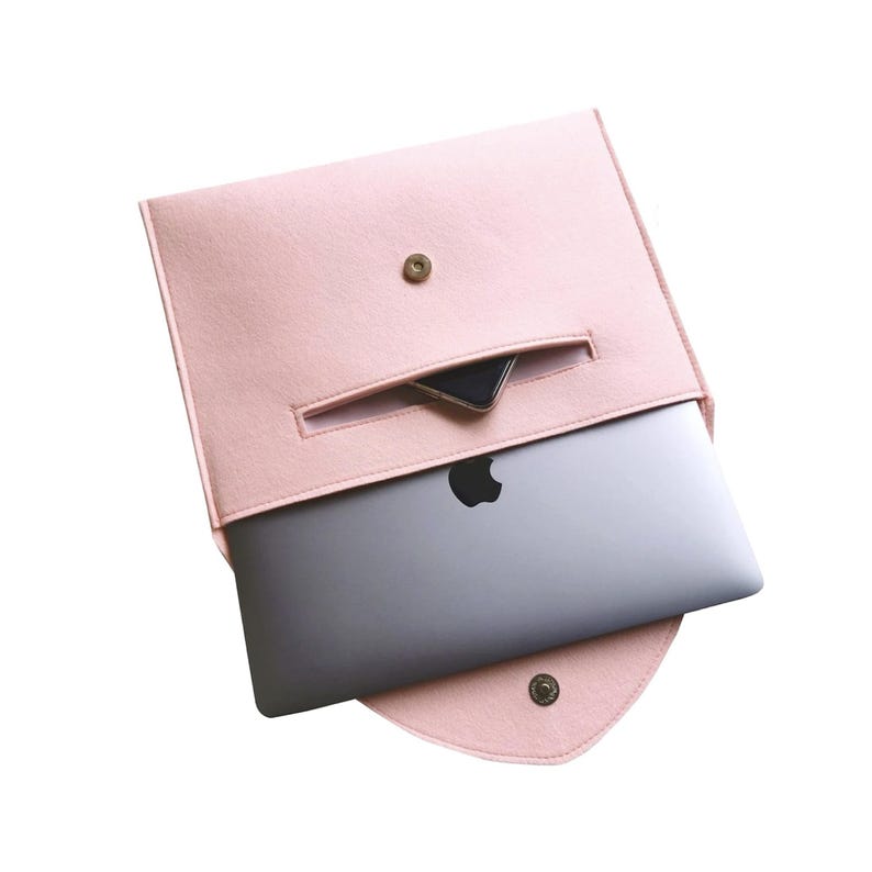 Pu&ograve; includere: Una custodia per laptop in feltro rosa con una piccola tasca sul davanti. Un laptop &egrave; all'interno della custodia.