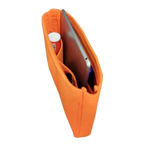 Op de afbeelding: Oranje gevoerde tasorganizer met meerdere vakken en compartimenten. Een tablet is zichtbaar in de tas.