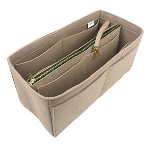 May include: Beige felt bag organizer with multiple pockets and a zippered compartment. The organizer has a gold zipper pull and a gold hook.