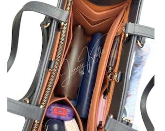 May include: A gray tote bag with a structured interior organizer. The interior features multiple compartments and pockets in shades of brown and orange, with various items stored inside. The bag has two handles and a zipper closure.