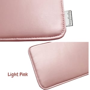 May include: Close-up of a light pink, rectangular item with rounded corners and stitched edges. The item has a smooth, leather-like texture. A small, rectangular tag with the text "JennyKrafts" is attached to the item.