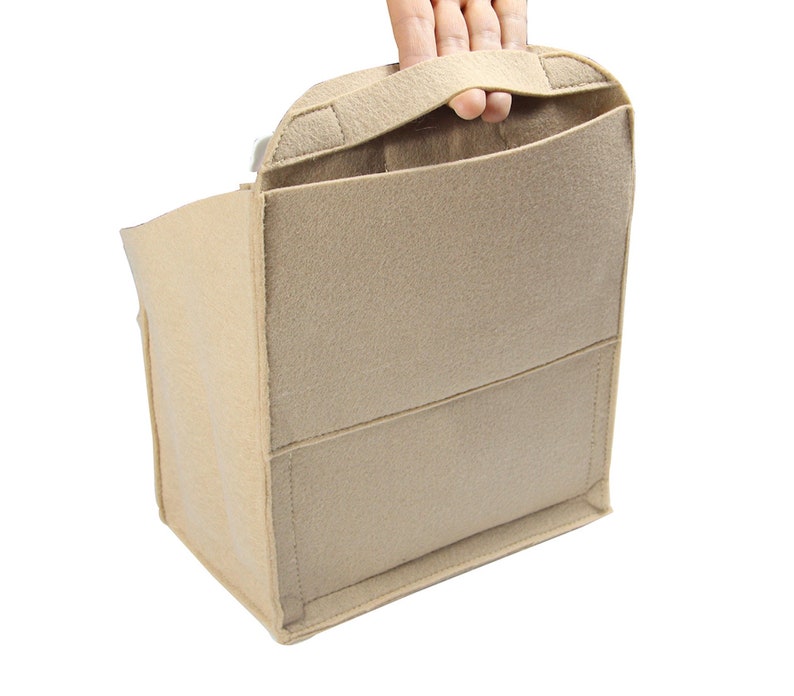 Op de afbeelding: Beige feltaschenorganizer met meerdere vakken en een handvat. De organizer is ontworpen om in een grotere tas te passen, waardoor items georganiseerd en gescheiden blijven.