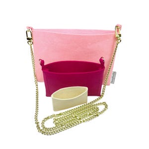 May include: A set of felt handbag organizers in shades of pink and fuchsia, with a gold chain strap. The set includes a large pink organizer, a smaller fuchsia organizer, and a beige insert, all designed to fit inside a handbag.