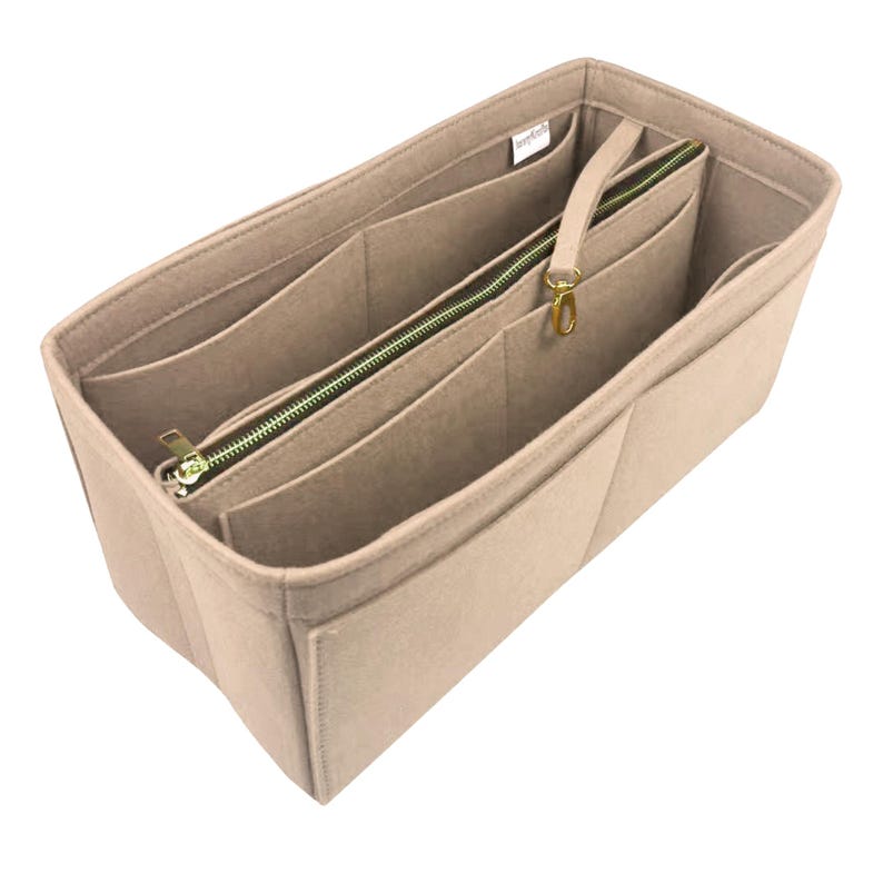 May include: Beige felt handbag organiser with multiple compartments and a zipped section. Features a gold-tone zip and a small handle with a gold-tone clasp. The organiser is designed to fit inside a larger bag.