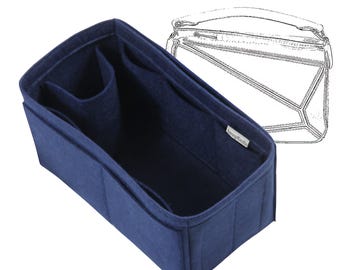 May include: A navy blue felt handbag organizer with multiple compartments. The organizer is rectangular with a structured design and a label on the inside. A sketch of a handbag is in the background.