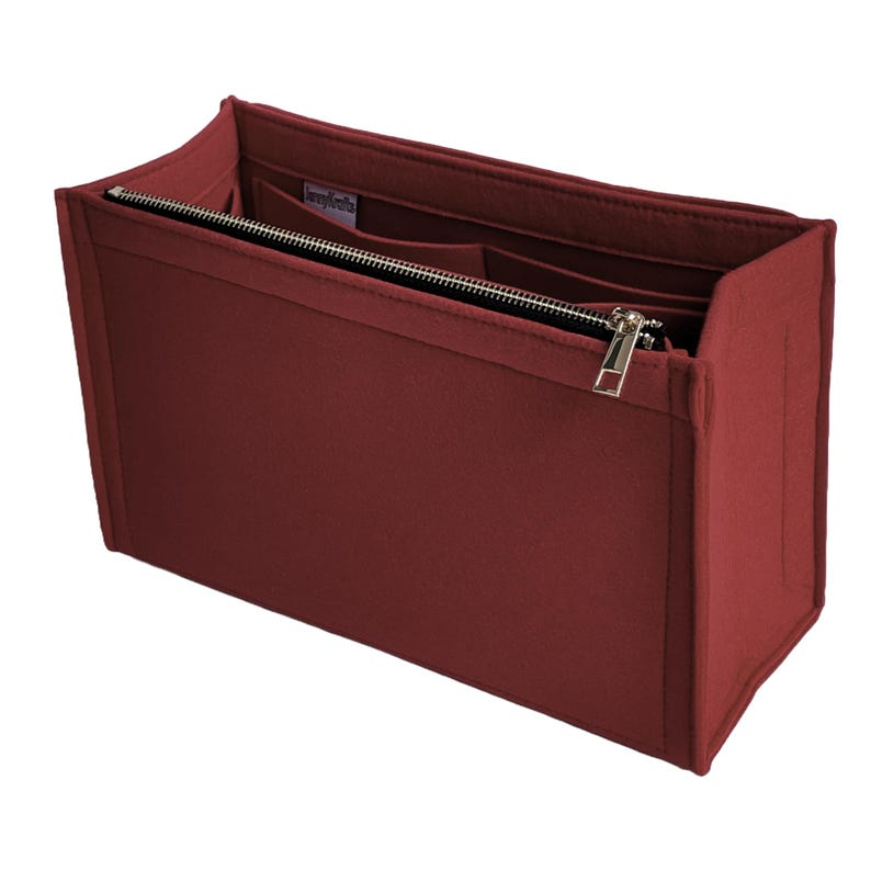 Op de afbeelding: Een bordeauxrode vilten handtassenorganizer met meerdere compartimenten en een ritssluiting. De organizer heeft een rechthoekige vorm en is ontworpen om in een grotere tas te passen. De rits en hardware zijn zilverkleurig.