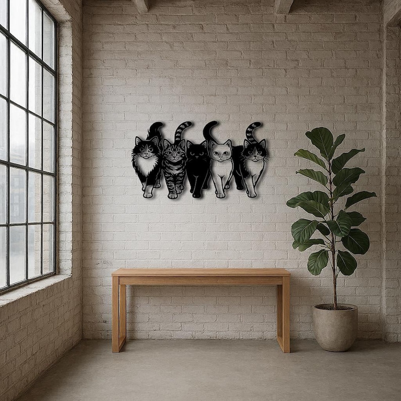 May include: A wall-mounted metal art piece featuring five stylized cat silhouettes. The cats are in various poses, with different patterns and colors, including black, white, and tabby. The artwork is mounted on a white brick wall above a wooden table.