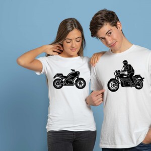 May include: White t-shirts with black motorcycle graphics. One shirt features a motorcycle, the other depicts a person riding a motorcycle. The shirts are worn by two people, set against a blue background.